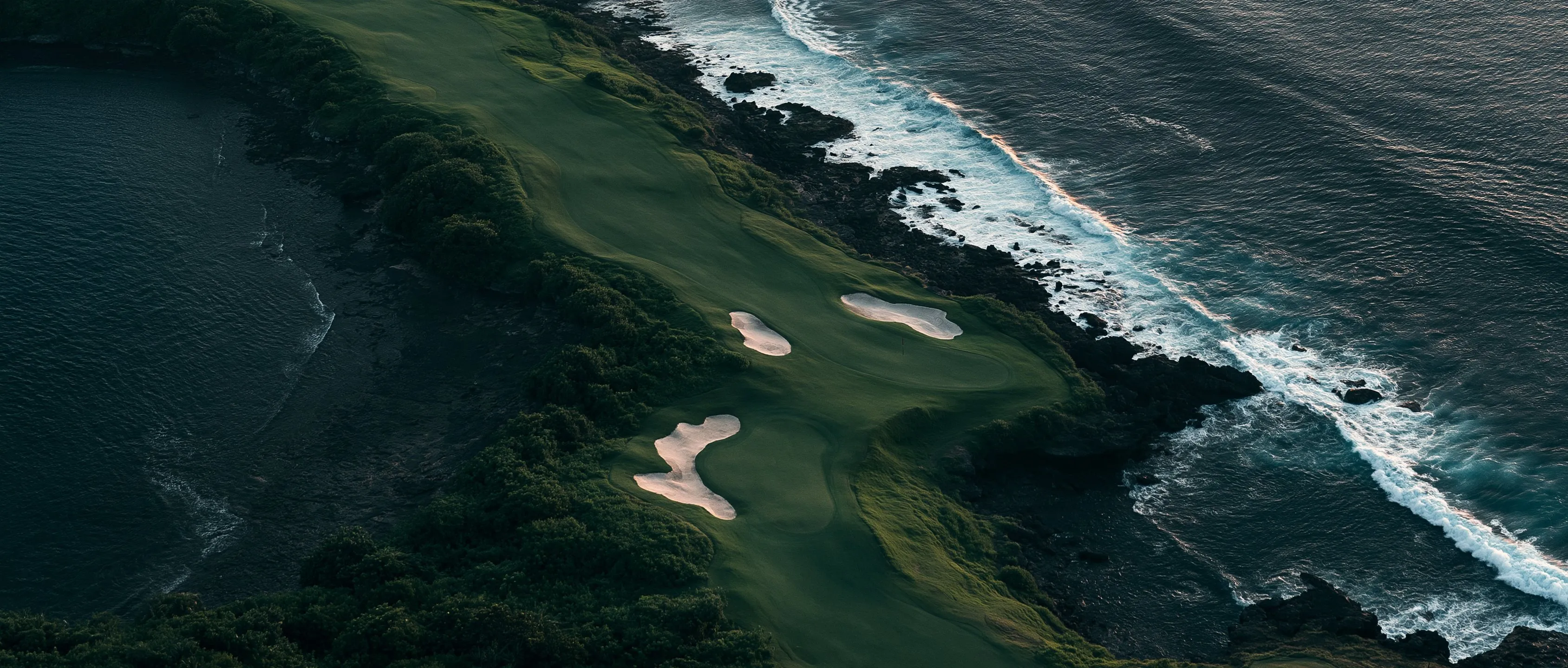 Foto udara lapangan golf di tepi laut saat senja